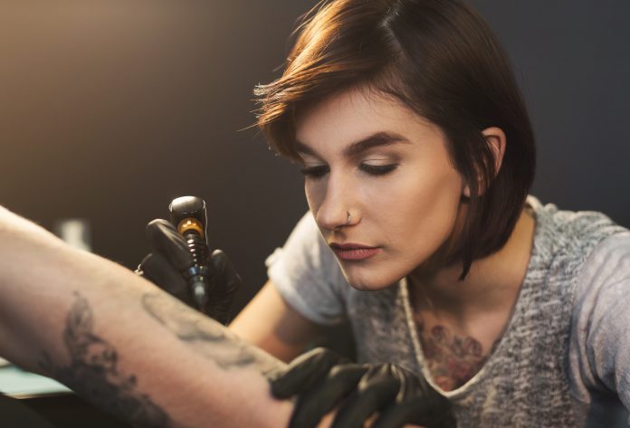 kobieta wykonująca tatuaż