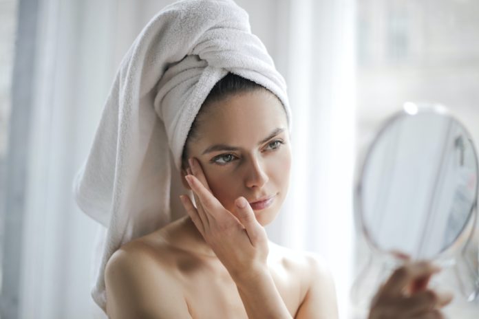 kobieta w ręczniku na głowie przed lustrem